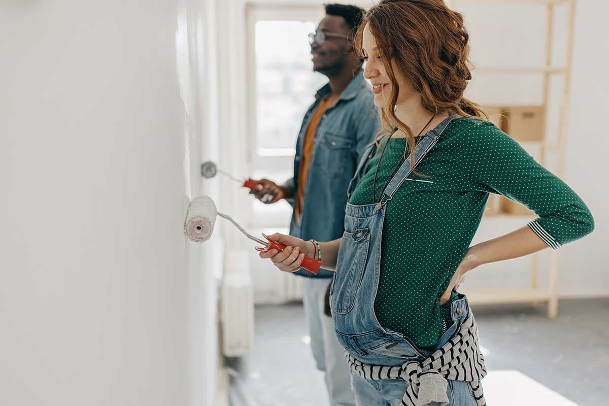 En mann og en kvinne maler en vegg sammen med sterke farger, og viser samarbeid og kreativitet