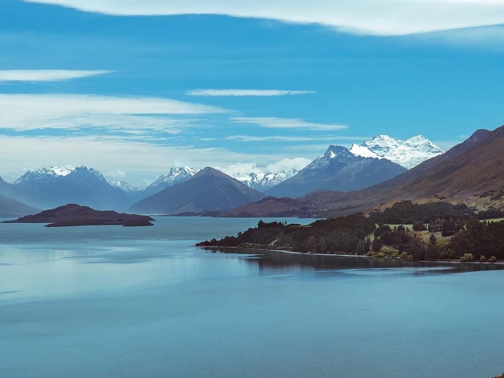 Naturskjønn utsikt over Lake Wakatipu i New Zealand, omgitt av fjell under en klar blå himmel