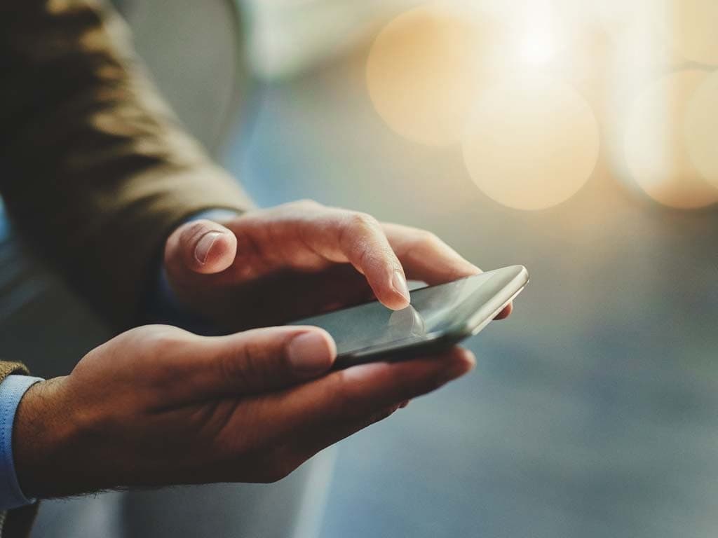 En person holder en smarttelefon i hånden og ser på skjermen med et fokusert uttrykk