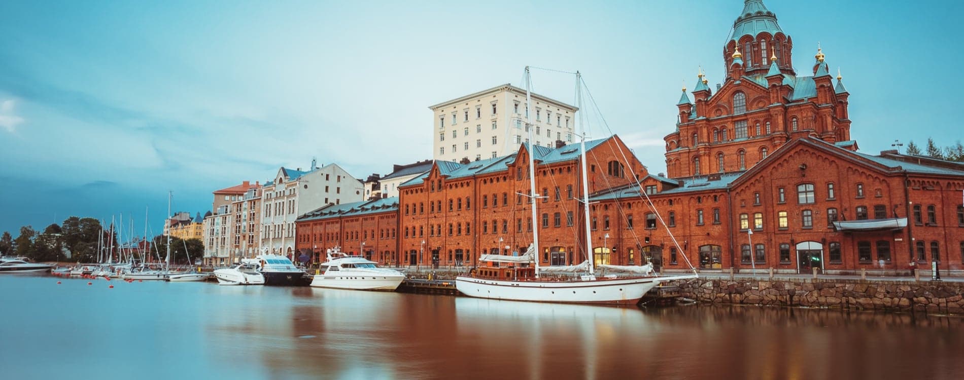 Den pittoreske havnen i Helsingfors, Finland, med sjarmerende gamle bygninger og båter under en klar himmel